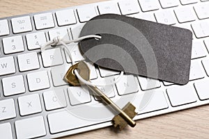 Key with blank tag and computer keyboard on table, closeup. Keyword concept