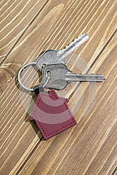 key chain with house symbol and keys on wooden background