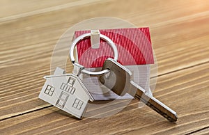 key chain with house symbol and keys on wooden background