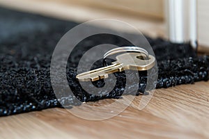key hidden partially under black doormat