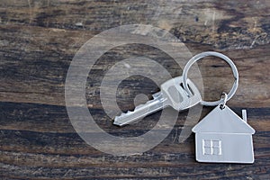 Key and House Pendant on a Rustic Wooden Background