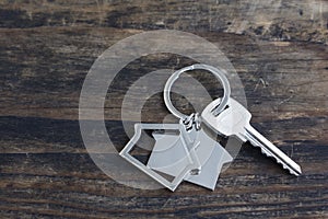 Key and House Pendant on a Rustic Wooden Background