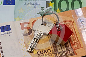 Key with house shaped key chain on euro banknotes