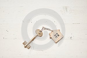 Key with house shaped keychain. Modern light lobby interior. Mortgage concept. Real estate, moving home or renting