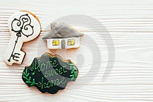 Key, house, welcome sign cookies on white wood, flat lay with space for text. Dream home concept. Home Sweet Home. Moving in new