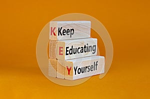 KEY, keep educating yourself symbol. Wooden blocks with words `KEY, keep educating yourself`. Beautiful orange background, copy