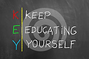 Key keep education yourself text on blackboard