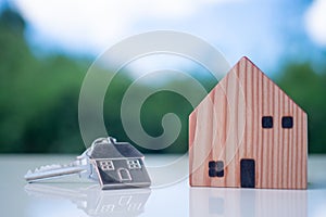 Key  and key chains in the shape of a silver house with a small brown wooden house model. New home concept, house for rent - buy,