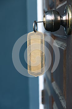 Key with metal empty keyring in wooden door knob