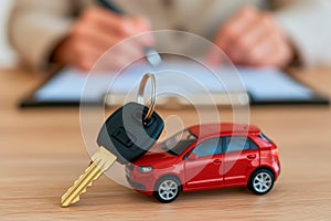 A key and a miniature red model car in a vehicle purchasing process concept