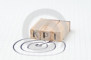 Key Performance Indicator, KPI concept, small wooden stamp combine the acronym KPI with hand draw arrow and target on white grid