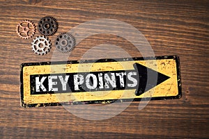 Key Points. Direction arrow and miniature gears on wood texture background