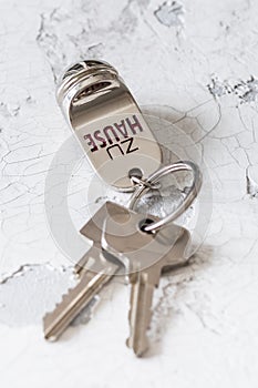 Key ring with two keys and tag with German text Zu Hause (translation: at home) on a white background