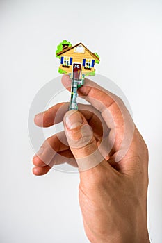 Key in the shape of a house in the hand on white background