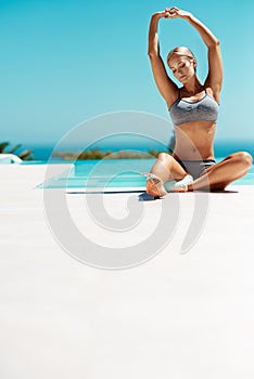 The key is in the stretch. an attractive young woman in workout gear stretching by the pool after her workout on a sunny