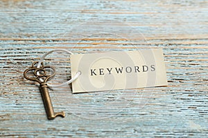 Key with tag KEYWORD on blue wooden background