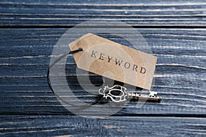 Key with tag KEYWORD on blue wooden background