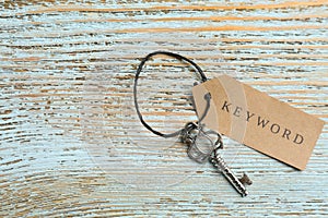 Key with tag KEYWORD on blue wooden background, top view. Space for text