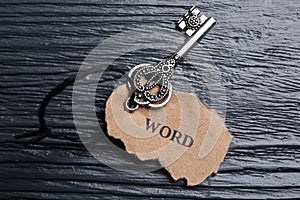 Key with tag WORD on black wooden background, top view. Keyword concept