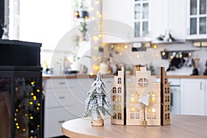 Key and tiny house of a small size on cozy home with Christmas decor on table of festive white kitchen. Gift for New Year.