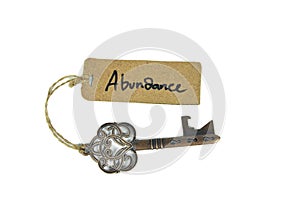 Key to abundant life concept - Old key with abundance tag isolated on white background