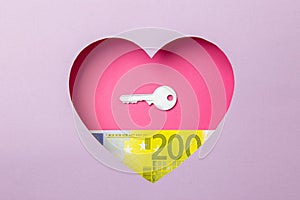 The key to the door and the two hundred euro banknote are in a pink heart on a purple background. Minimal concept of money, love