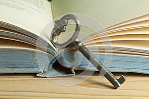 Key to knowledge concept. Book with key on wooden background.