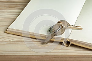 Key to knowledge concept. Book with key on wooden background.