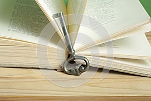 Key to knowledge concept. Book with key on wooden background.