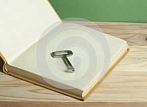 Key to knowledge concept. Open book with key on wooden background.