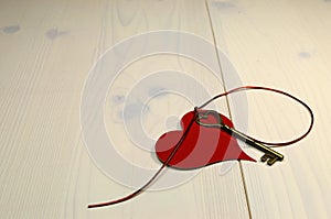 'Key to My Heart' love concept, with gold heart shape key and red heart on white shabby chic wood table