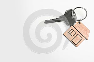 Key with trinket in shape of house isolated on white. Real estate agent services