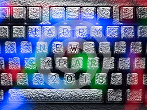 Keyboard covered with snow with title happy new year 2018 lit by colorful lights