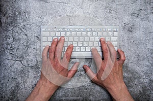 Keyboard with hands on a dark gray background. Asphalt concrete wallpaper. Context, writer, programmer, office work.