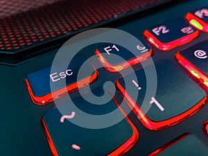 Keyboard of laptop highlighted by red lights