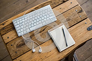 Keyboard, notepad, earphones on rustic wooden table photo