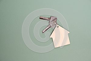 Keychain in form house with keys green background.Concept buying house, apartment or rent