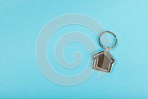 Keychain in the shape of a house with a key ring on background.