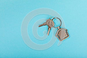 Keychain in the shape of a house with a key ring on background.