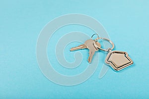 Keychain in the shape of a house with a key ring on background.