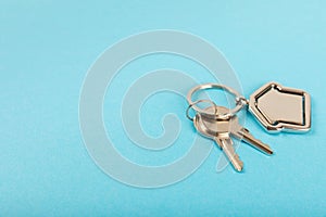 Keychain in the shape of a house with a key ring on background.