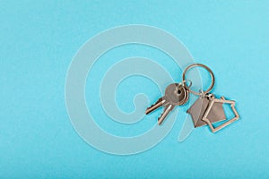 Keychain in the shape of a house with a key ring on background.