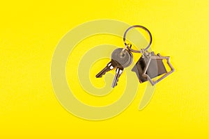 Keychain in the shape of a house with a key ring on background.