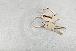 Keychain in the shape of a house with a key ring on background.