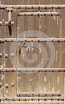 Keyhole in an old paneled wooden door with antique door handle; rusty and weathered