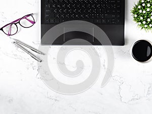Keypad laptop with glasses silver pen coffee cup flower vase on marble table workplace copy space