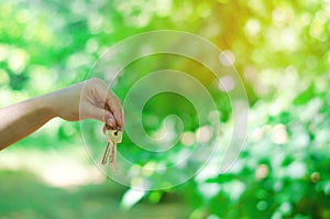 Keys in hand in park outdoors. concept of real estate. sale and purchase of an apartment, housing in the forest and on the nature.
