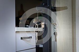 Keys hanging from the lock of an open house door. Home security, real estate concept
