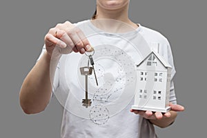 Keys from house concept. woman holds small house and keys in her hand. Buy real estate. Real estate services for buying your home