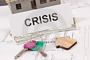 Keys with house shape, dollar and inscription crisis on housing plan. House under contruction. Crisis of real estate market.